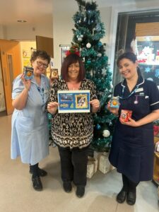 Woman with two female nurses with chocolate oranges in front of Christmas tree